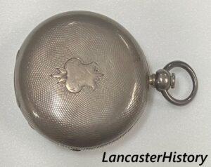 Closed front cover of silver pocket watch.