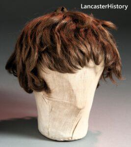 A brown wig sitting on a stand