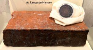 A round coin sitting on top of a red brick