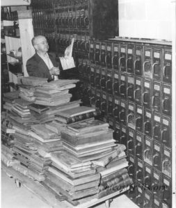 Ira Kreider handling county documents with pile of books in the foreground.