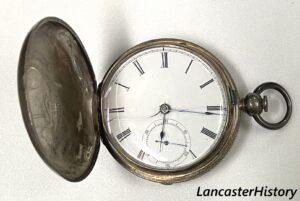 Open front cover of silver pocket watch showing clock face