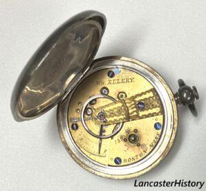 Open back cover of silver pocket watch showing clock movement