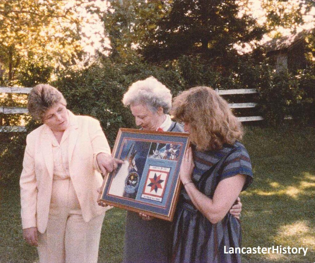 A group of women looking at a framed plaque.