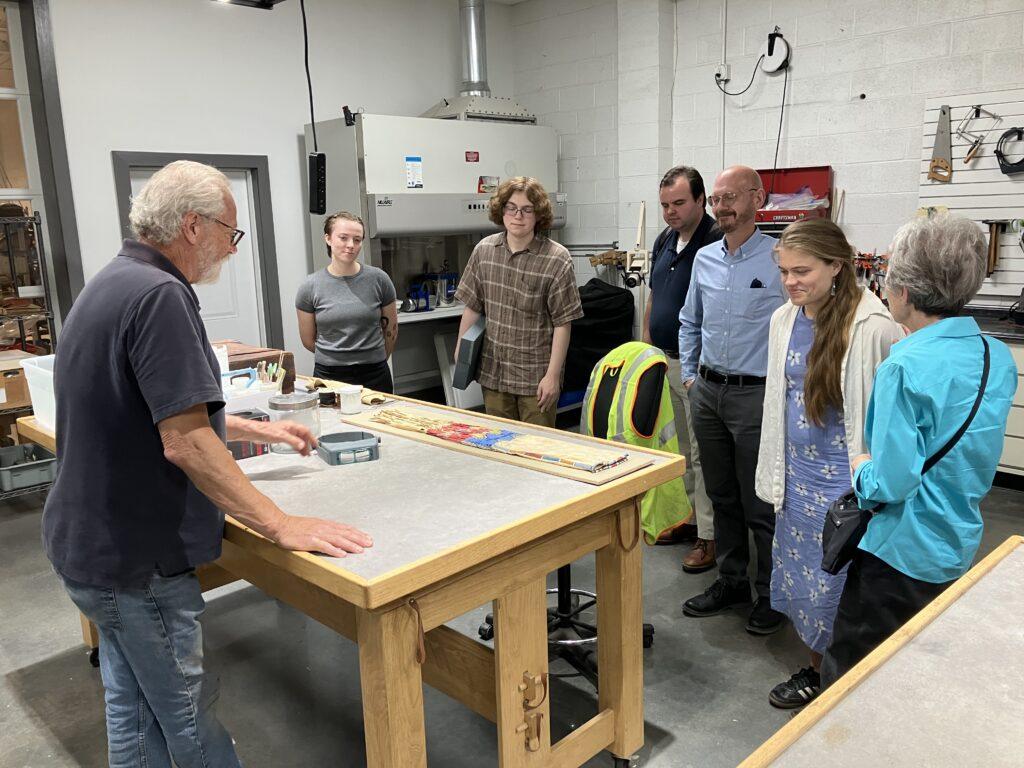 Group of people looking at objects on a table.