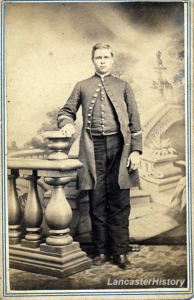 A carte de visite of James Cunningham. He stands posed in a military-like coat, leading against a decorative pillar.