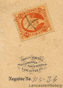 A tax stamp found on the back of a carte de visite. Stamped text says "Thos. Cummings. Photographer North Queen St. Lancaster, PA."