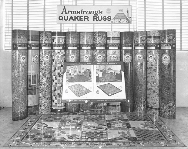 A historic image of a Quaker Rug promotion staged by a Los Angeles wholesaler in March 1941. The promotion includes vertical rolled stacks of flooring and a section of Play Rug pattern number 4595