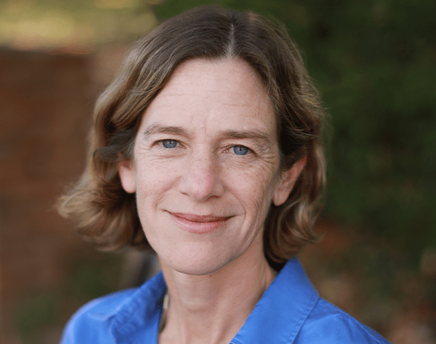 Headshot of an older woman with light skin, short brown hair, and a blue collared shirt.