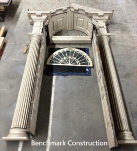 Wooden pieces of an ornate doorframe spread out on a floor.