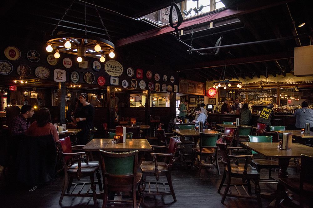 A photograph of the inside of the Horse Inn. The dining room features multiple tables with rustic chandeliers hanging from the ceiling.