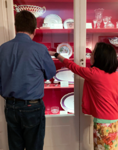 Two individuals standing in front of the cabinet pointing to the Buchanan china on exhibit.