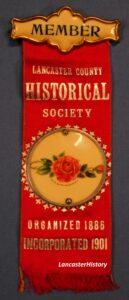 Red ribbon with celluloid red rose button in center