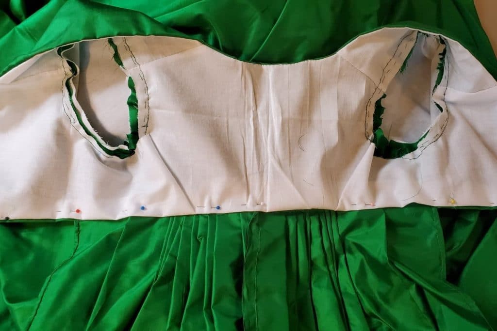 The bodice turned right side up with the back skirt panels underneath. The white lining is pinned, encasing the raw edges of the bodice and back skirt.