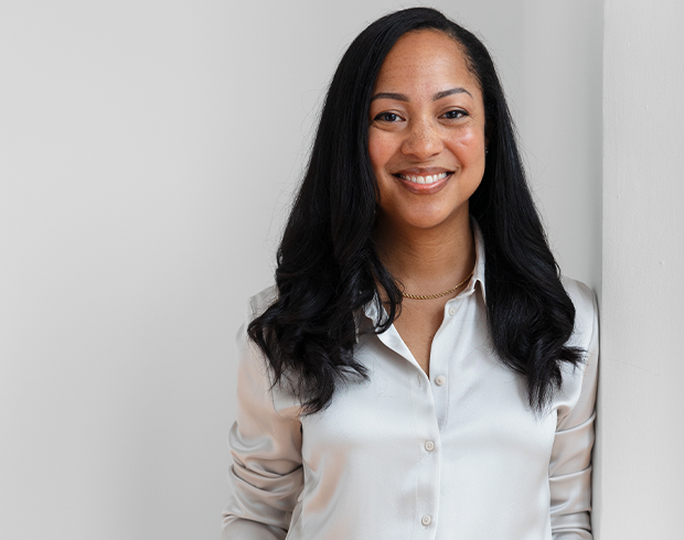 A young woman with long black hair and brown skin in a white button down shirt.