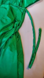 Length of green silk folded and pinned in order to create tie closure