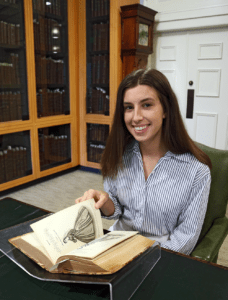 A young student sits at a desk with a historic book in front of them.