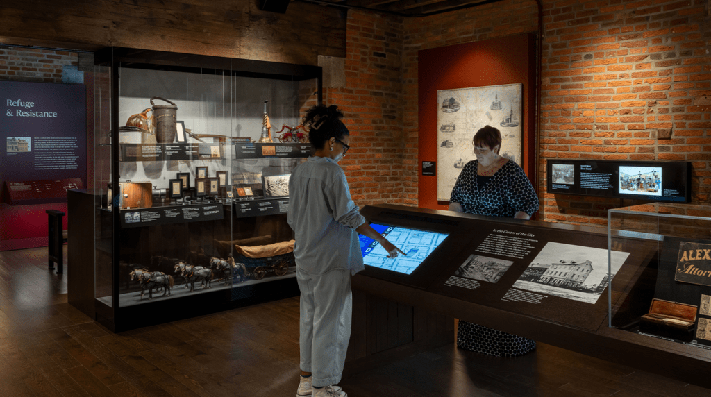 Two women look at and tap touchscreens in the "Lancaster in the 1800s" gallery at the Stevens & Smith Center.