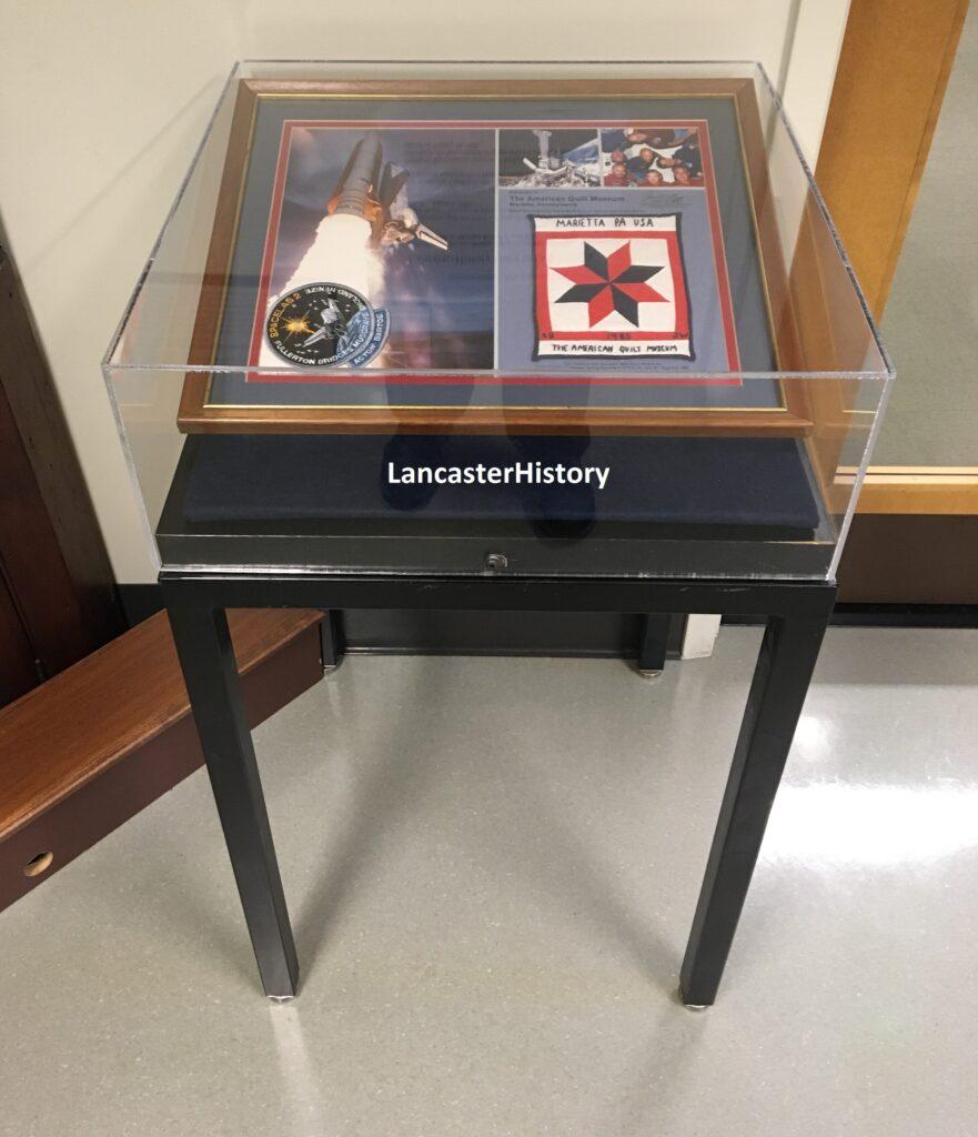 An exhibit case containing the space quilt plaque.