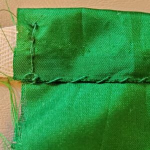 A back stitch holding the cotton tape ties in place at the ends of the bodice front piece.