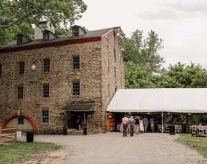 In the distance is a large, stone mill with a tent attached.