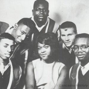 A black and white historic photograph of five men and one woman.