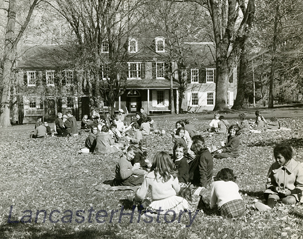 A black and white photo of the Wheatland lawn with many children sitting in the grass.