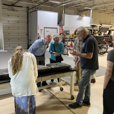 <i> Leather carriage seats removed for examination.  </i> Group of people looking at leather seats.