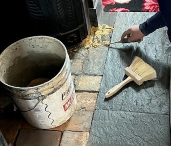 <center><i>Hurst applies a fresh sand pointing for new firebox bricks.</center></i> A man applies a neat line of sand around the edges of the bricks.