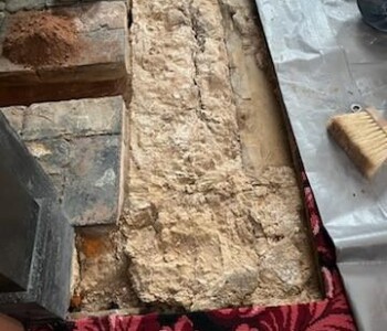 <center><i>After breaking down the slate, the next step was to clean the hearth and firebox of all debris.</i></center> The old slate was removed, showing the ground and stone beneath the previous slate hearth.