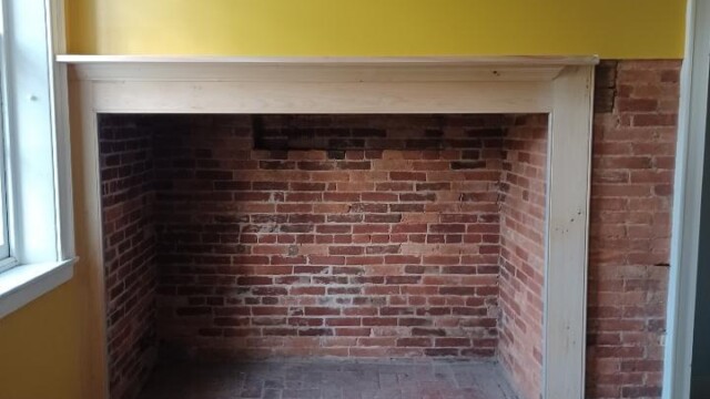 Wooden mantle installed over the fireplace.