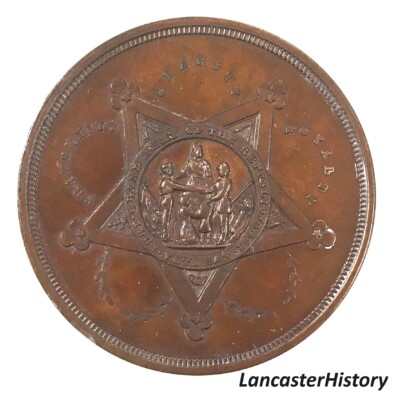 <i> Commemorative coin front, GAR Department of Pennsylvania Annual Encampment, Lancaster, 1884. LancasterHistory, Gift of Civil War Museum of Philadelphia. </i> Cooper coin with GAR symbol in center.
