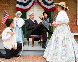 Costumed reenactors gather around a reenactor portraying James Buchanan.