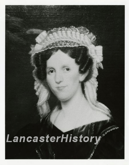 A black and white photograph of a painting of a light-skinned woman. She has tightly curled hair at her temples and the top of her head is covered in a bonnet-like hair piece. She wears a dark gown with a v-shaped neckline. Her right eye appears to look off more to the right than her left. 